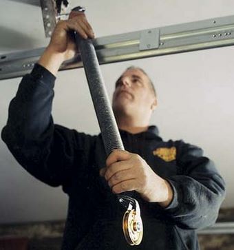 A worker replacing garage door spring pulley; image courtesy Jayla Barnsen